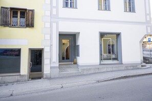 Ein Gebäude mit weißer Fassade, einer Tür mit Fensterglas und einem Fenster, in dem die Werbung 'Gold Pieces' zu sehen ist.