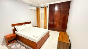 Un dormitorio con cama, mesita de noche, armario y una pequeña mesa.