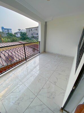 A balcony with a tiled floor and a decorative metal railing.