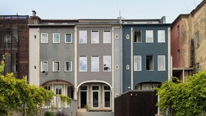 Une cour avec une petite pelouse, deux chaises blanches et un bâtiment doté de nombreuses fenêtres et d’une porte.