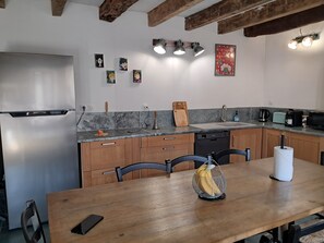 A modern kitchen with wooden cabinets, a stainless steel refrigerator, a sink, and a dining table with chairs. - Vacation home in Lozère (Gorges du Tarn Causses)