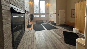 A spacious room with a fireplace, large windows, and a bench. - True Ski In/Out on Maryland Parkway Trail Chair #4 (Brian Head)