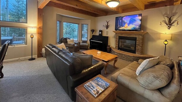 A cozy living room with a fireplace, a piano, and a television. - True Ski In/Out on Maryland Parkway Trail Chair #4 (Brian Head)