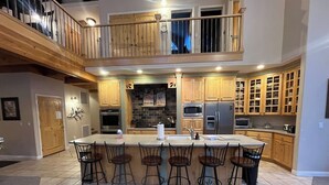 A spacious kitchen with a central island, bar stools, and a mezzanine level. - True Ski In/Out on Maryland Parkway Trail Chair #4 (Brian Head)