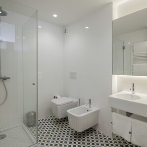 A modern bathroom with a glass shower enclosure, a toilet, a bidet, and a sink with a mirror. - Penthouse with Private Balcony | Baumhaus Serviced Apartments | Central Porto (Porto)