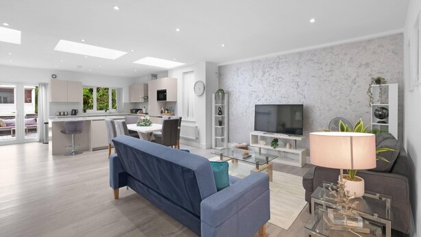 A modern living room with a sofa, TV, and a glass coffee table. - Modern 3 Bedroom, 2 Bathroom Home in Edgware (Edgware)