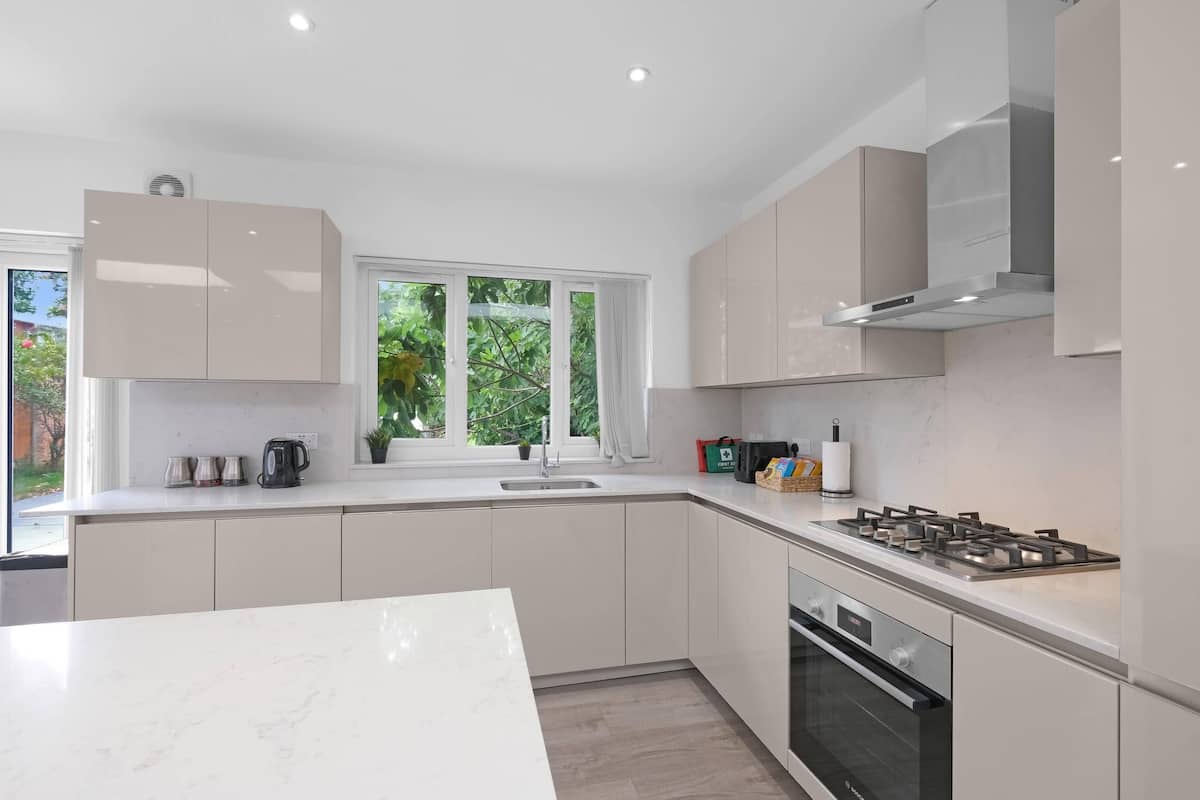 A modern kitchen with white cabinets, a gas stove, and a built-in oven.