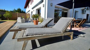 Ein Poolbereich mit zwei Liegestühlen, einer Holzterrasse und einem Blumentopf.