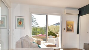 Ein modernes Wohnzimmer mit einer Couch, einem Holztisch und einer Glastür zum Außenbereich.