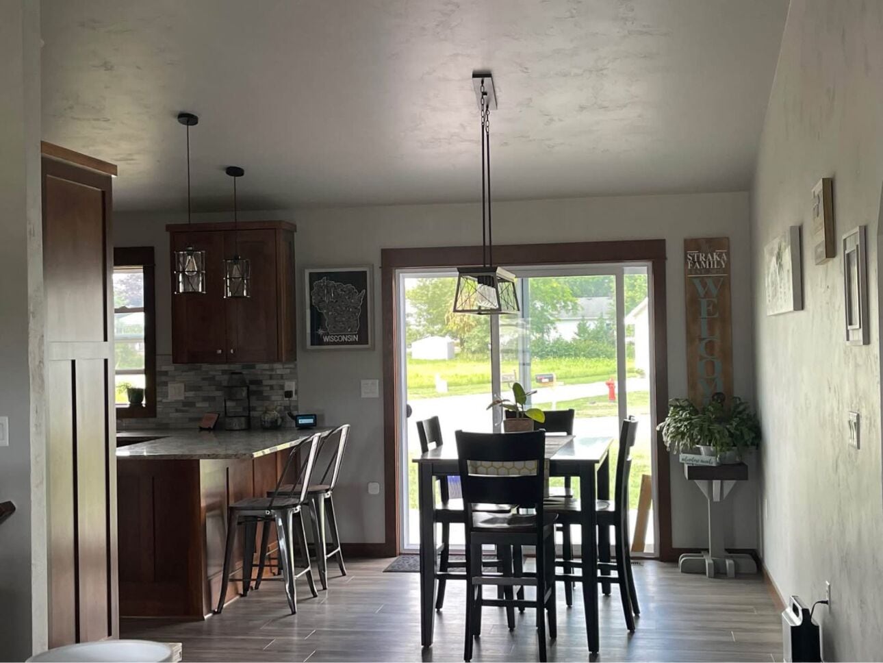 A modern kitchen with a large island, bar stools, and a dining area with chairs.