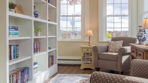 A living room with a bookshelf, two armchairs, a patterned rug, and a chandelier.