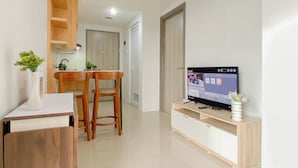 A modern living room with a TV, wooden furniture, and a small dining area. - Contemporary And Restful 2Br At Apartment Anwa Residence (South Tangerang)