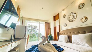 A hotel room with a bed, a desk with a computer, a TV, and decorative wall mirrors. - Modern Style Studio At Art Deco Apartment (Bandung)