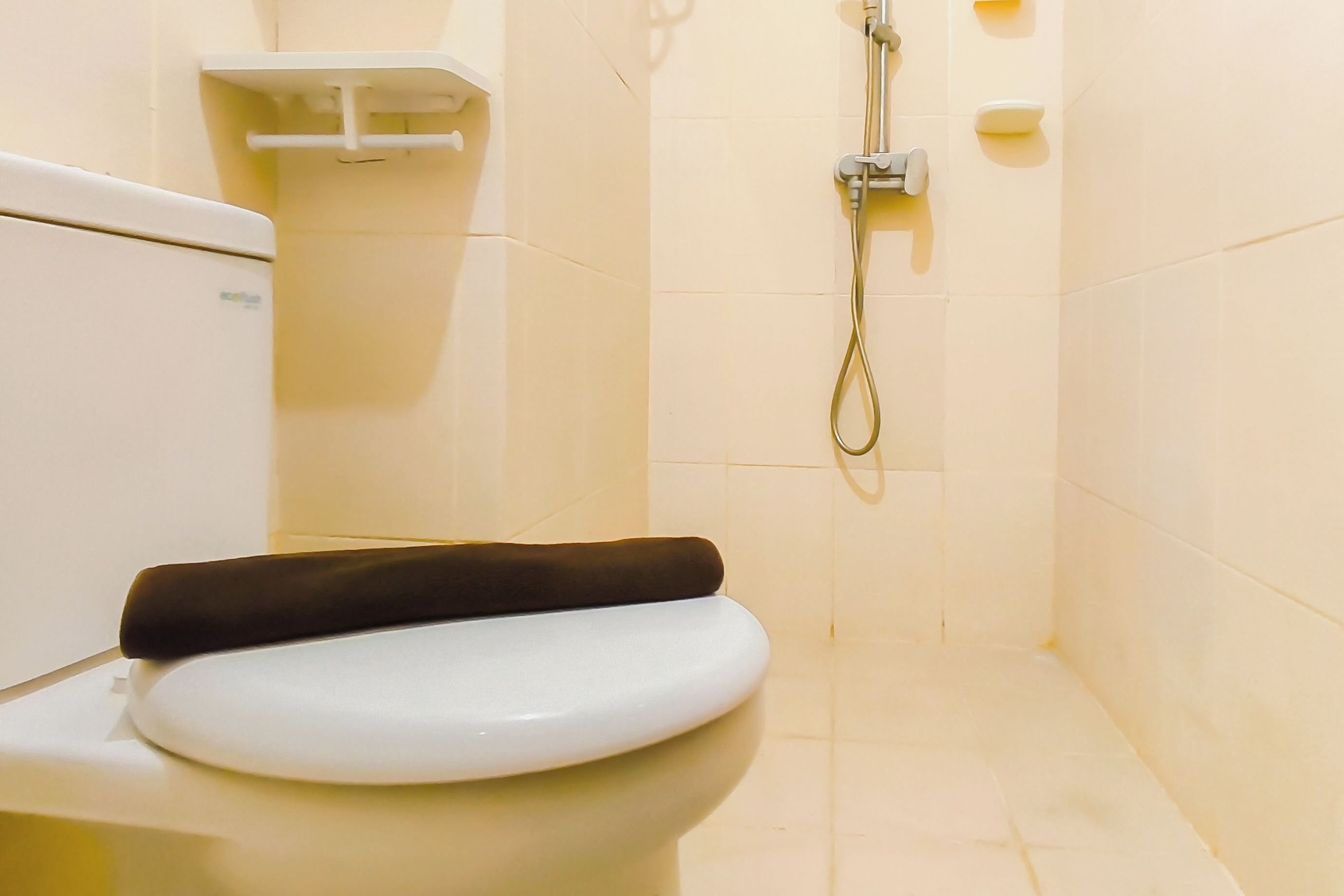 A bathroom with a toilet, a shower, and a white tiled wall.