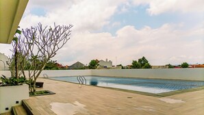 A swimming pool with steps leading down to it, surrounded by a low wall and some greenery. - Studio Apartment Near Upn Veteran Yogyakarta At Barsa City (Depok)