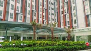 A modern building with a glass entrance and a red and white facade. - Studio Apartment Near Upn Veteran Yogyakarta At Barsa City (Depok)
