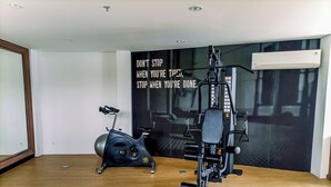 A gym with a stationary bike, a weight machine, and a motivational poster on the wall. - Studio Apartment Near Upn Veteran Yogyakarta At Barsa City (Depok)