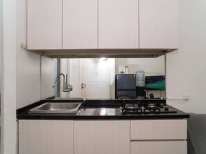 A compact kitchen with a sink, stove, and a water dispenser. - Neat And Nice 2Br At Apartment Bassura City (Jakarta)