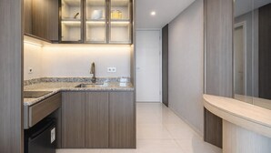 Une cuisine moderne dotée d’un îlot central intégré, d’un évier en acier inoxydable et de meubles de rangement en bois.