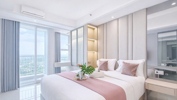Une chambre d’hôtel moderne avec un grand lit, une table de chevet, un miroir et une vue sur la ville.