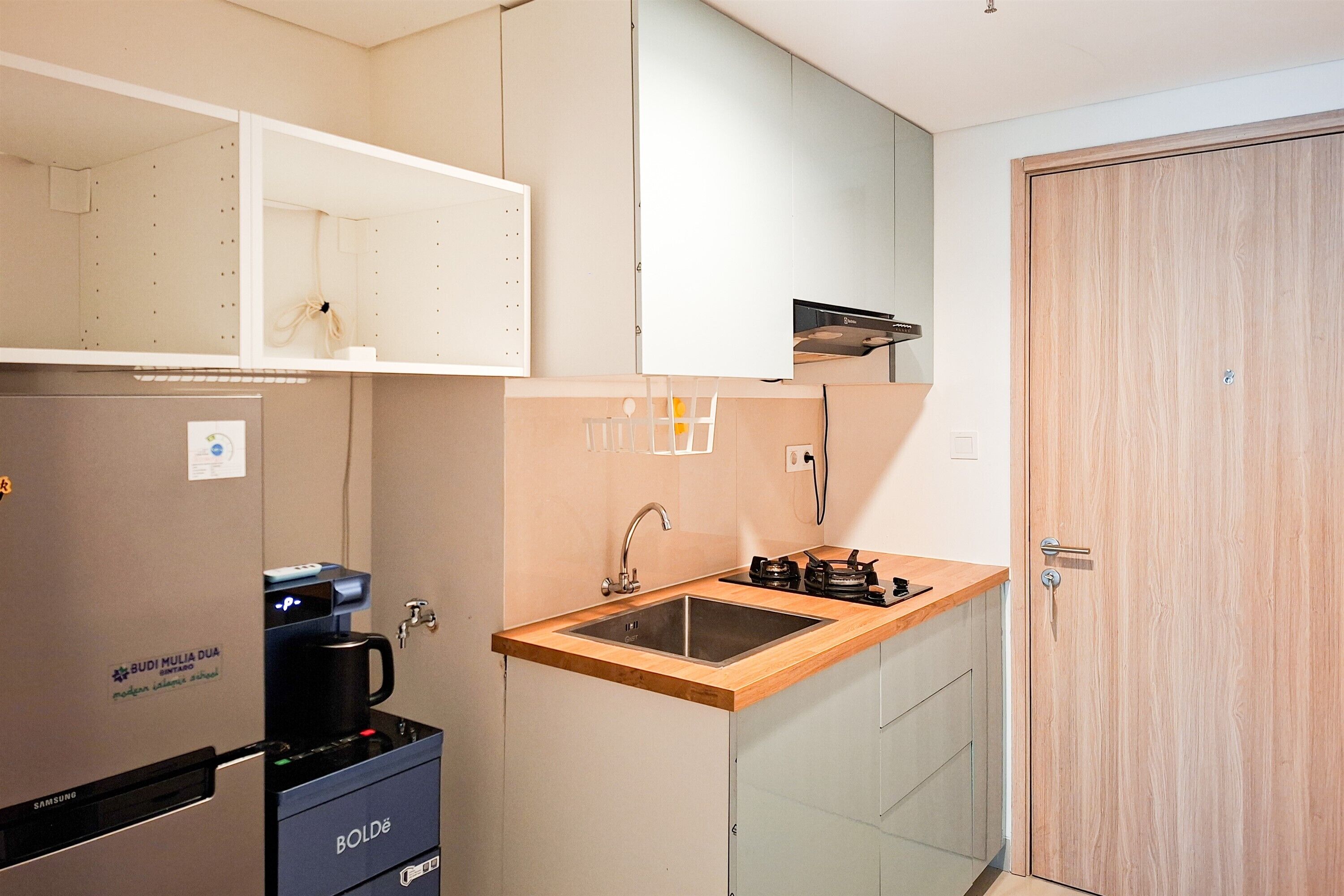 A compact kitchen with a built-in coffee machine, a sink, and a refrigerator.
