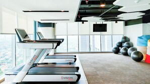 Een sportschool met loopbanden, fitnessballen en uitzicht over de stad.