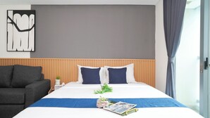 Een moderne hotelkamer met een bed, een bank, een kunstwerk aan de muur en een raam met gordijnen.
