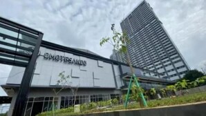 Een modern gebouw met het bord 'OMOTESANDO' en een hoge wolkenkrabber op de achtergrond.
