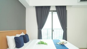 Een hotelkamer met een bed, een houten hoofdbord, grijze gordijnen en een balkon.