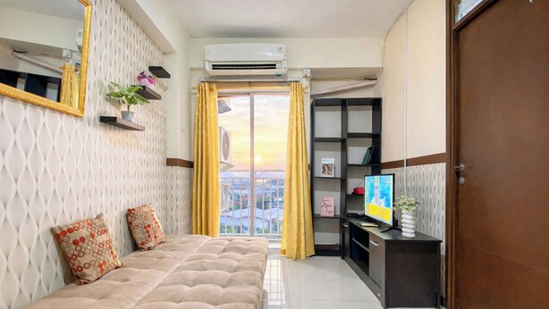 Una camera da letto con un letto, una televisione, un armadio e un balcone con tende.
