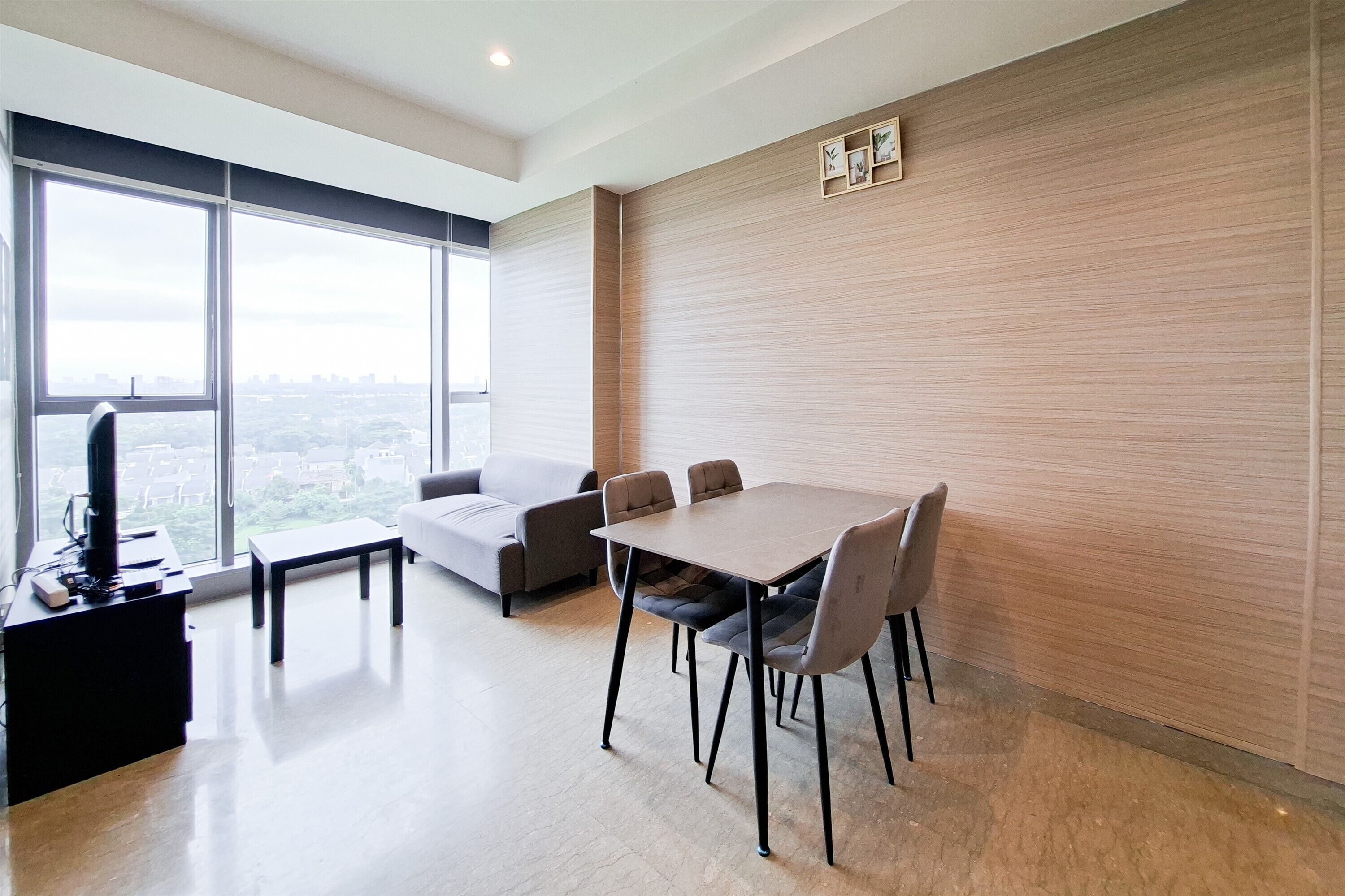 A modern room with a dining table, chairs, a sofa, and a TV.