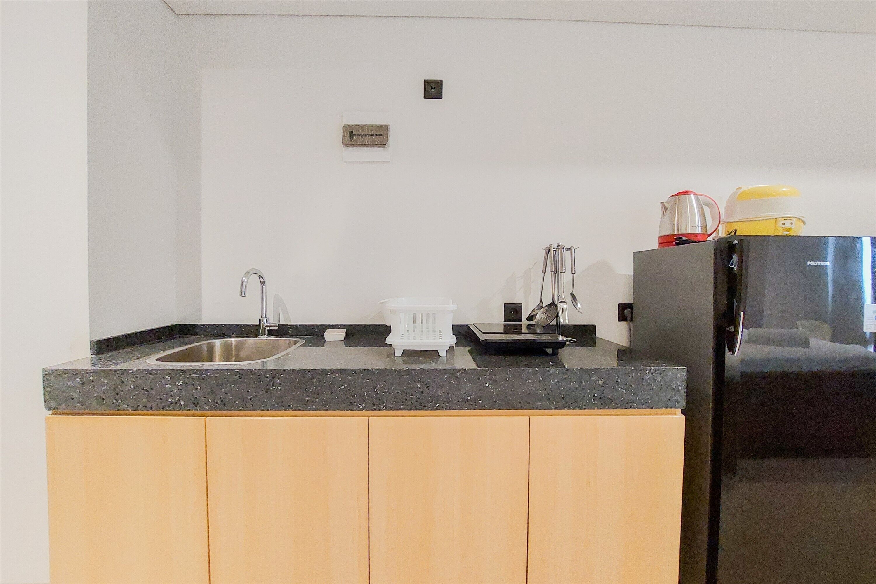 A kitchen with a granite countertop, stainless steel sink, and a black refrigerator.