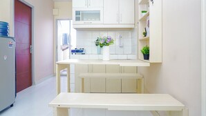 A compact kitchen with white cabinets, a countertop, a sink, and a small potted plant. - Homey 2Br For 4 Pax At Cibubur Village Apartment (Depok)