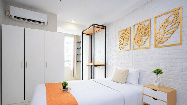 A bedroom with a bed, wardrobe, bedside table, and decorative leaf wall art. - Comfortable Classic Studio At Apartment Cinere Bellevue Suites (Depok)