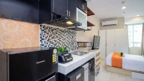 A compact kitchen with a refrigerator, microwave, and sink. - Comfortable Classic Studio At Apartment Cinere Bellevue Suites (Depok)