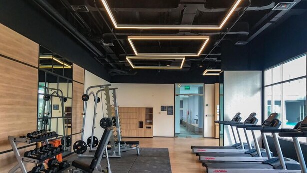 Ett gym med utrustning för styrketräning, löpband och en spegel.