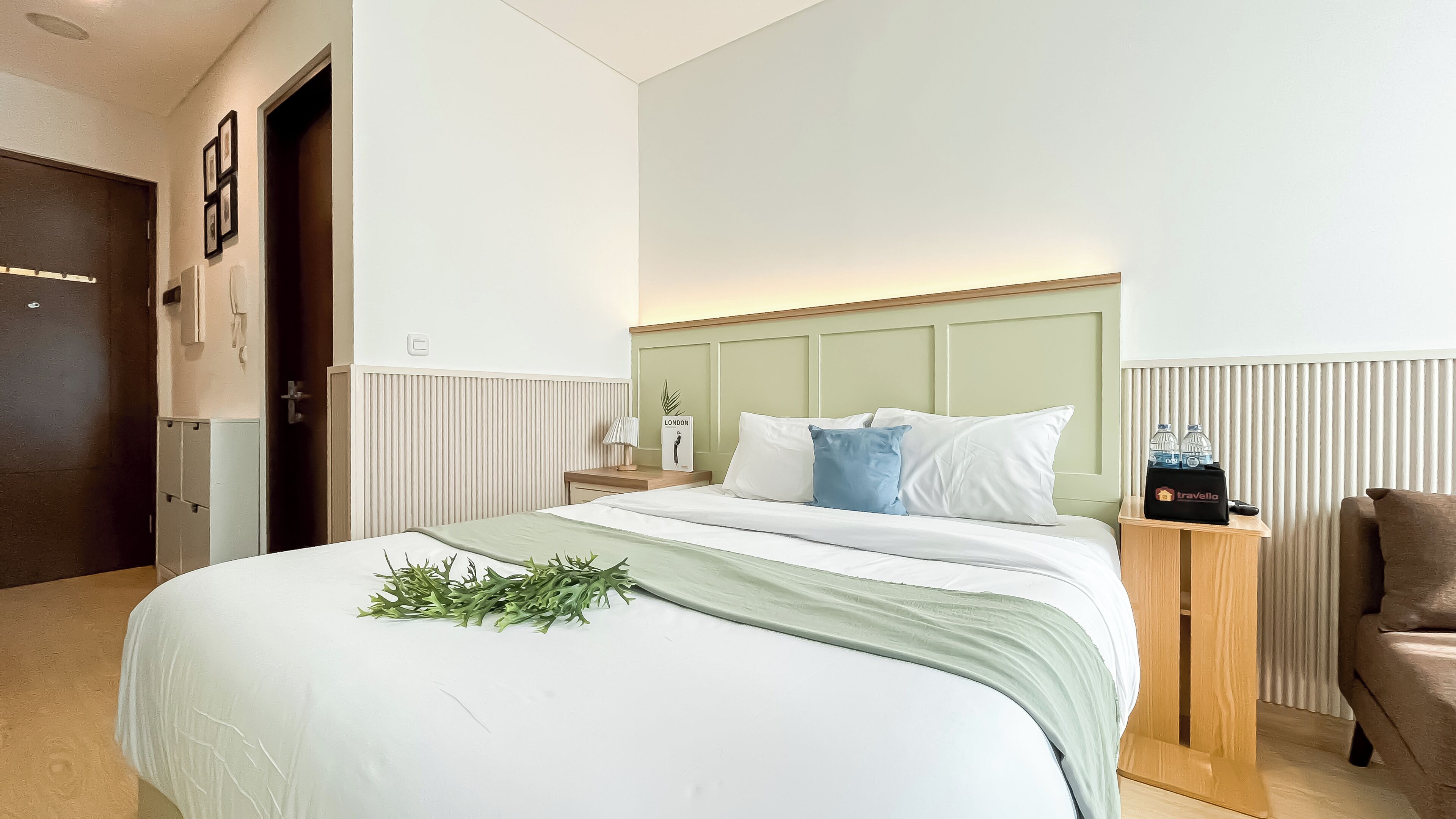 A hotel room with a bed, bedside table, lamp, and a chair.