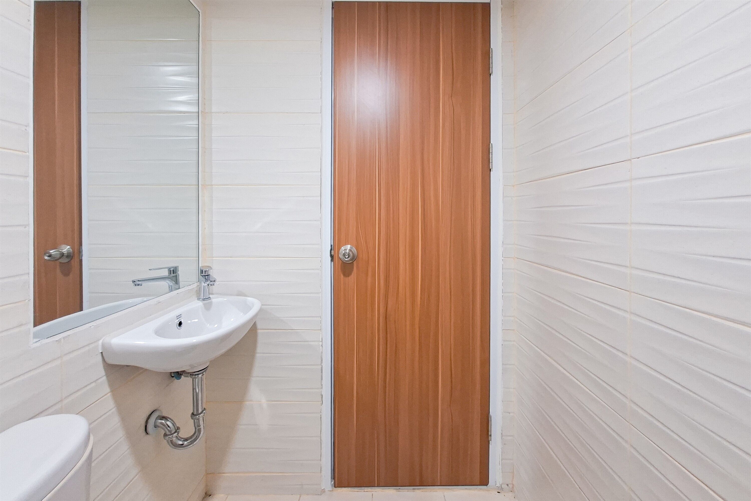 A bathroom with a white sink, mirror, and wooden door.