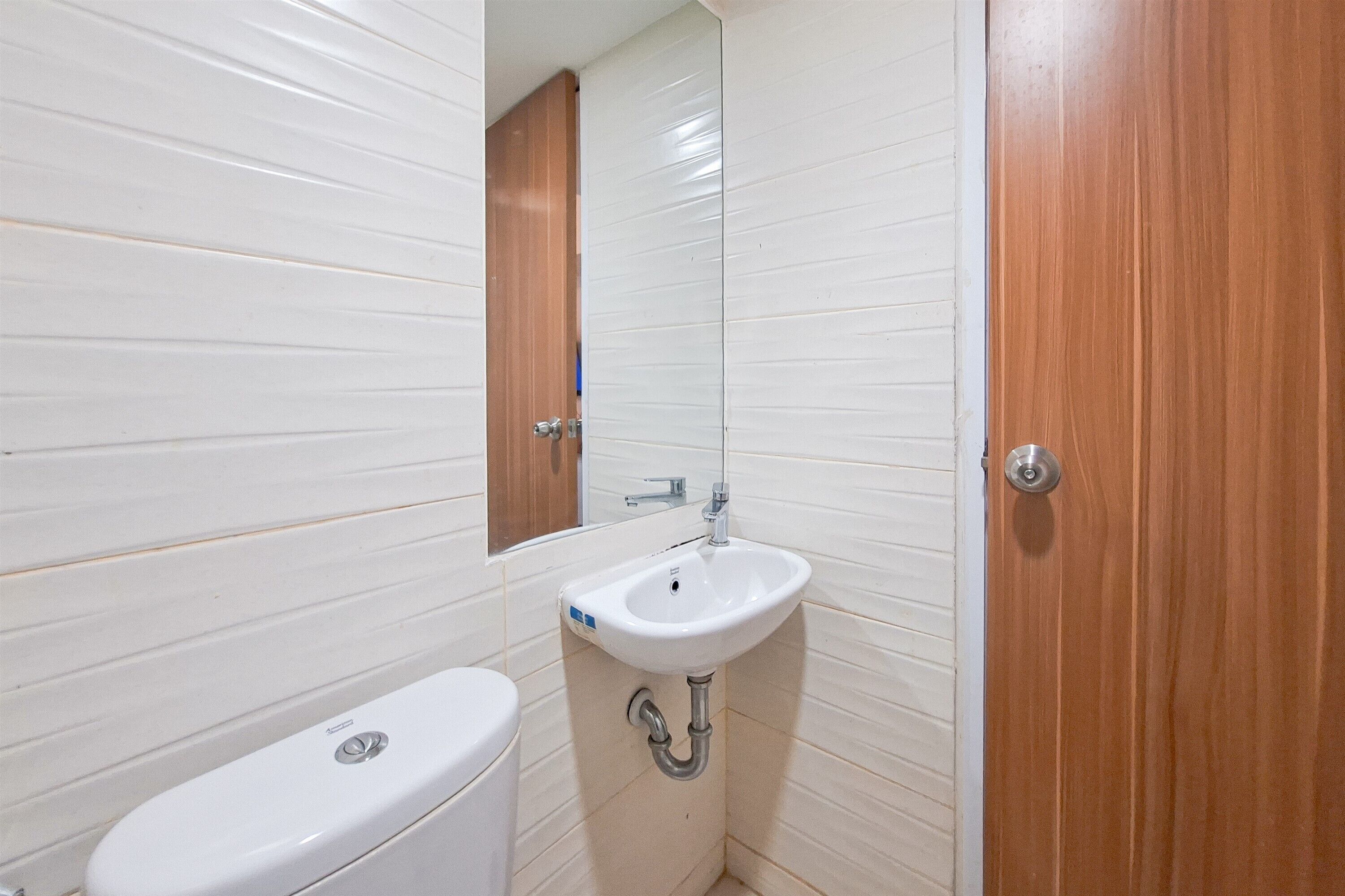 A small bathroom with a white toilet, a white sink, and a wooden door.
