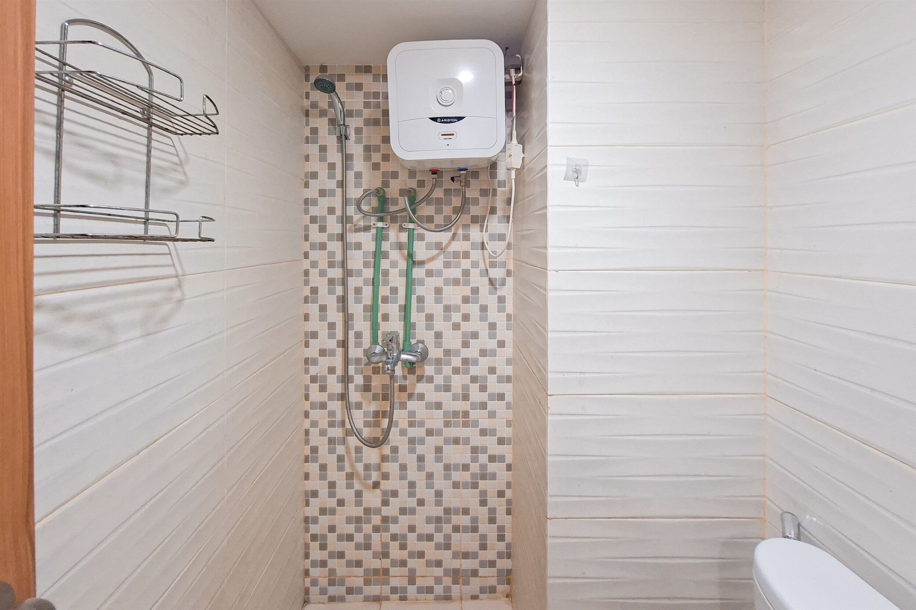 Une petite salle de bain avec une douche, des toilettes et un porte-serviettes.