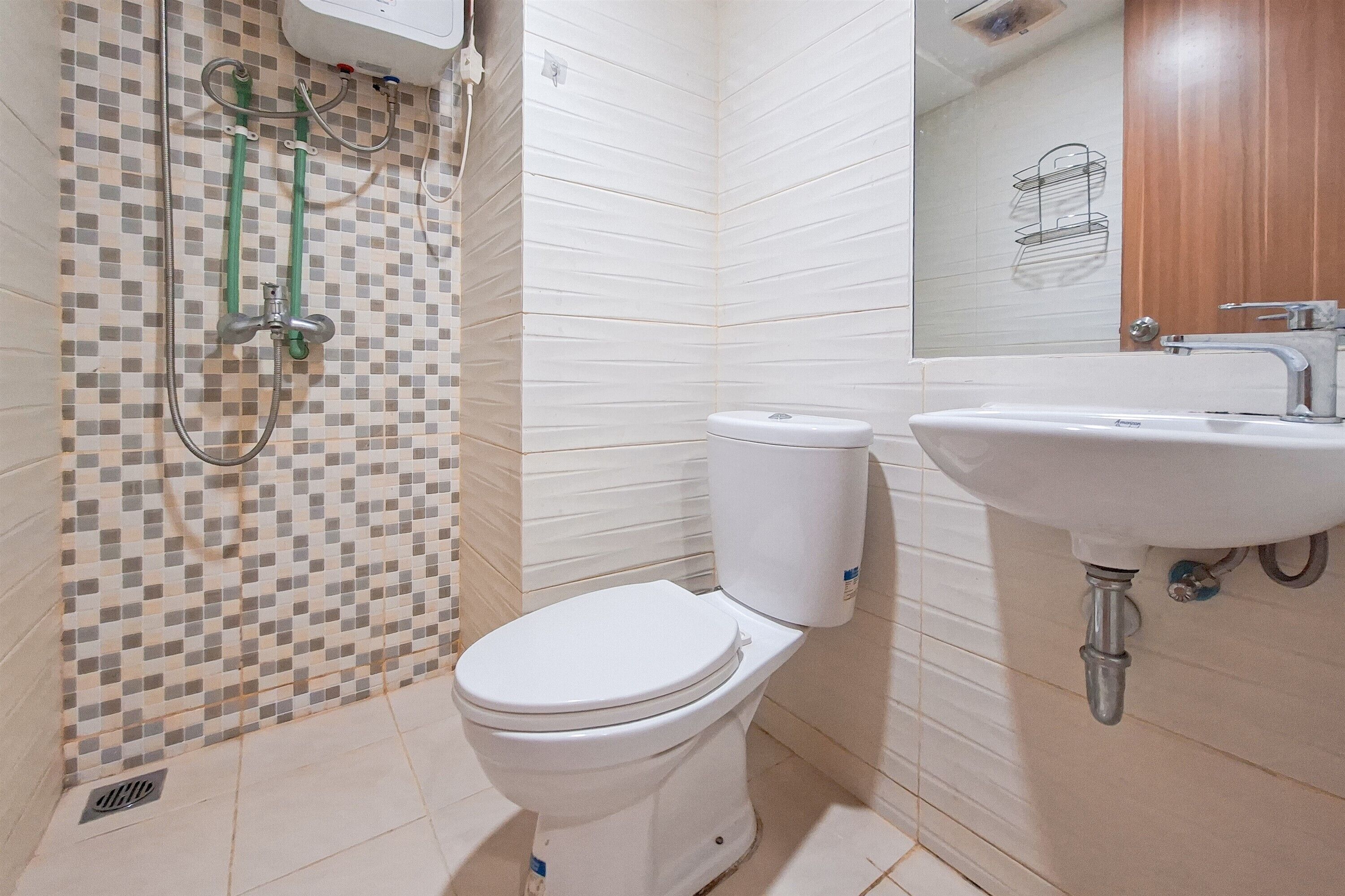 A bathroom with a toilet, a sink, and a shower with a tiled wall.