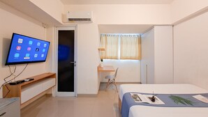 Camera d'albergo con televisione a schermo piatto, una scrivania con sedia, un letto e un armadio.