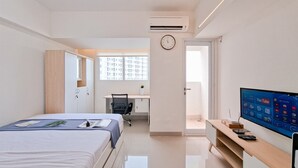 Ett modernt hotellrum med en säng, ett skrivbord, en stol, en TV och utsikt över staden genom fönstret.