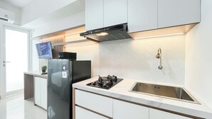 A modern kitchen with a stainless steel refrigerator, a gas stove, and a built-in oven. - Homey And Minimalist Studio At Apartment Cisauk Point (Cisauk)