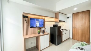 A compact kitchen with a built-in TV, a refrigerator, and a wooden countertop. - Homey And Minimalist Studio At Apartment Cisauk Point (Cisauk)