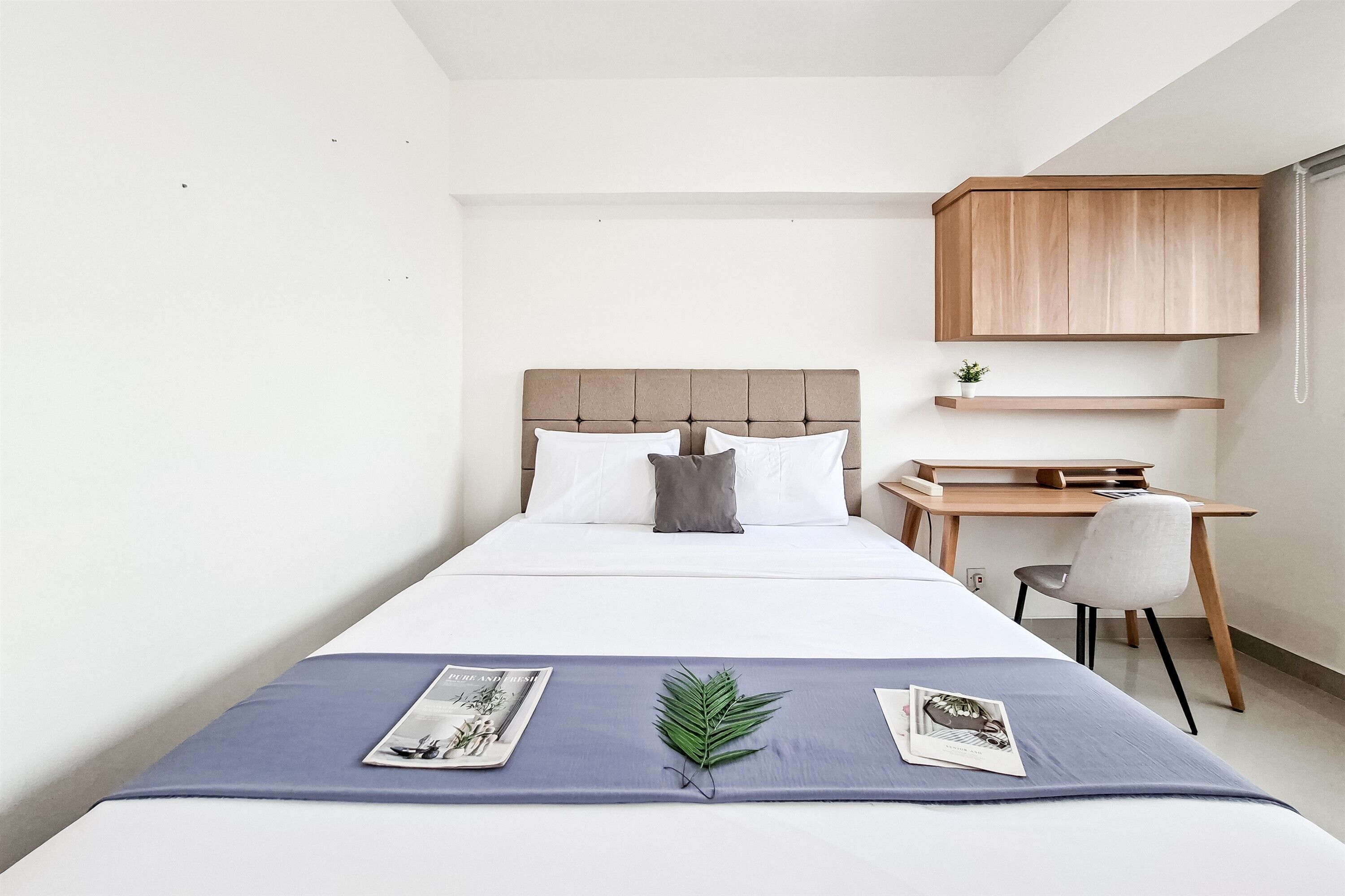 A bedroom with a bed, a desk, and a chair.