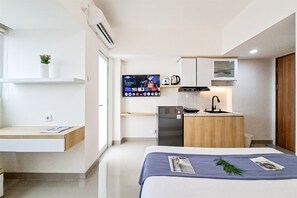 A compact hotel room with a bed, a small kitchenette, a TV, and a window. - Minimalist Nook Studio At Cisauk Point Apartment (Cisauk)