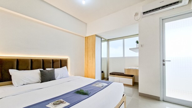 Ein modernes Hotelzimmer mit einem großen Bett, einem Nachttisch, einem Spiegel und einer Schiebetür zum Balkon.