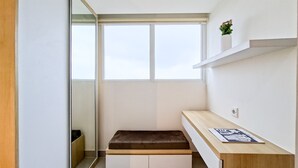 Ein schlichter Raum mit einer Bank, einem Holztisch und einem Fenster.