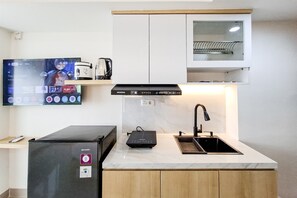 A modern kitchen with a built-in microwave, a coffee maker, a TV, and a sink. - Minimalist Nook Studio At Cisauk Point Apartment (Cisauk)